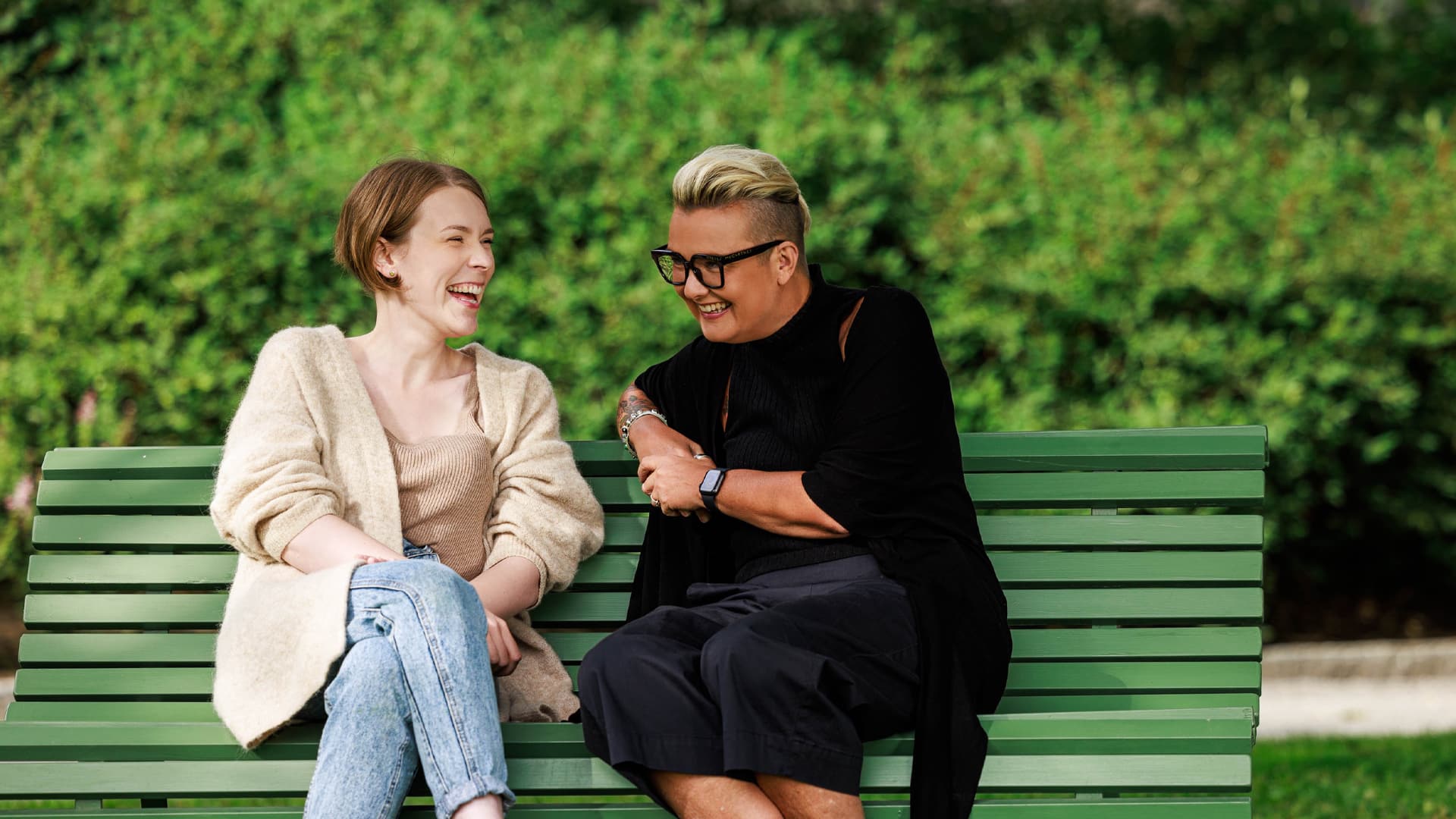 Two women sitting on a bench laughing