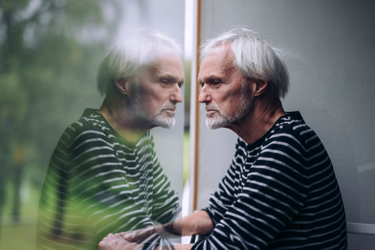 A man looking out of the window. The reflection of his face in the glass.