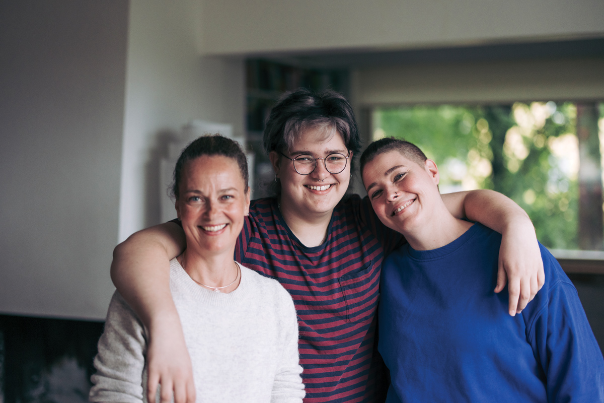 A teen age boy in the middle, two women on the sides.